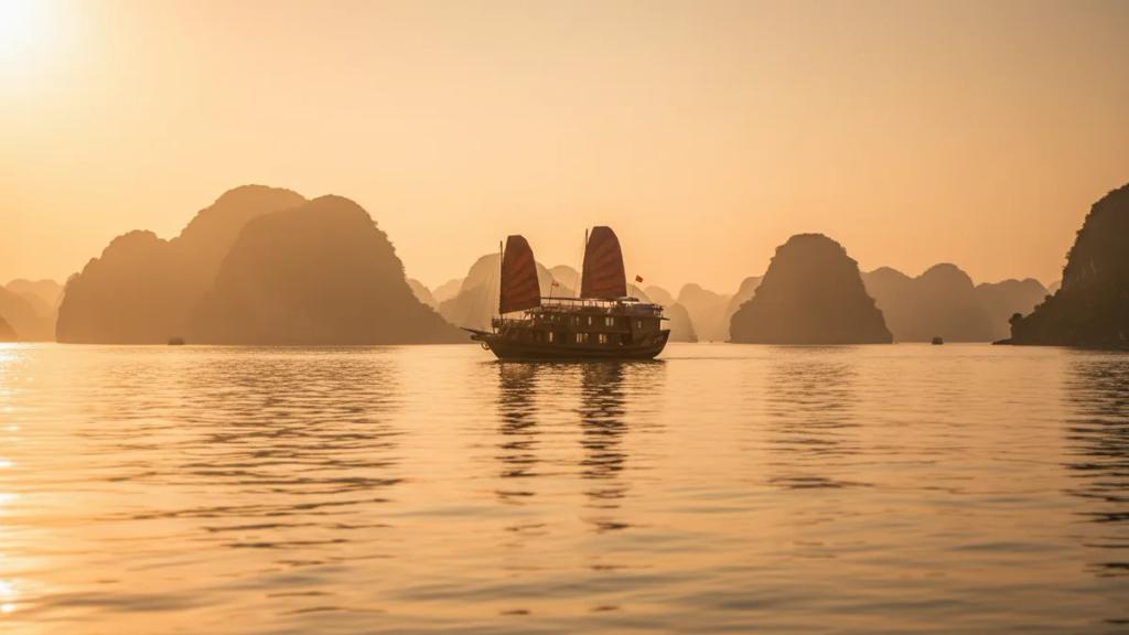 Wooden boats on an emerald bay beneath towering limestone karsts at golden hour
