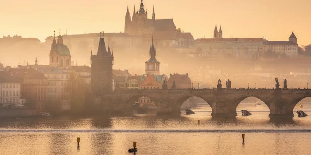 Charles Bridge statues and Prague Castle rising through morning mist
