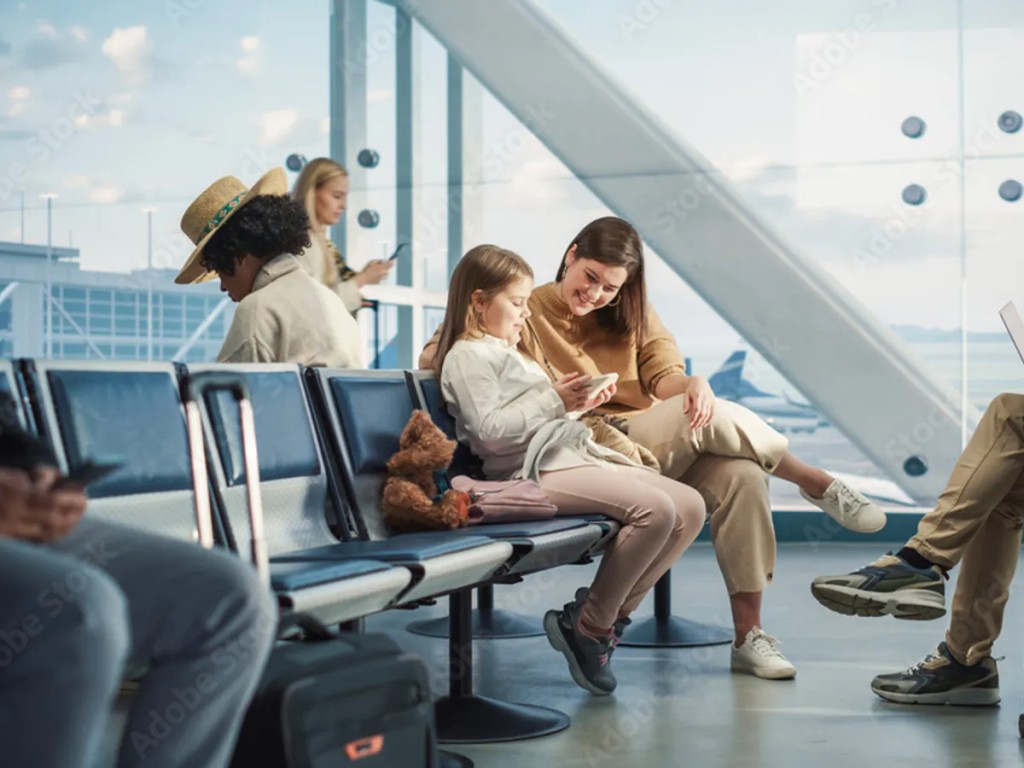 Travelers checking smartphones with travel eSIM at an international airport