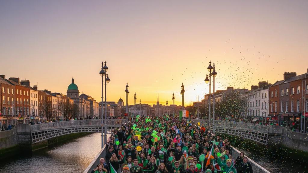 Crowds in green lining O'Connell Street in Dublin as a St Patrick's Festival parade float passes the GPO